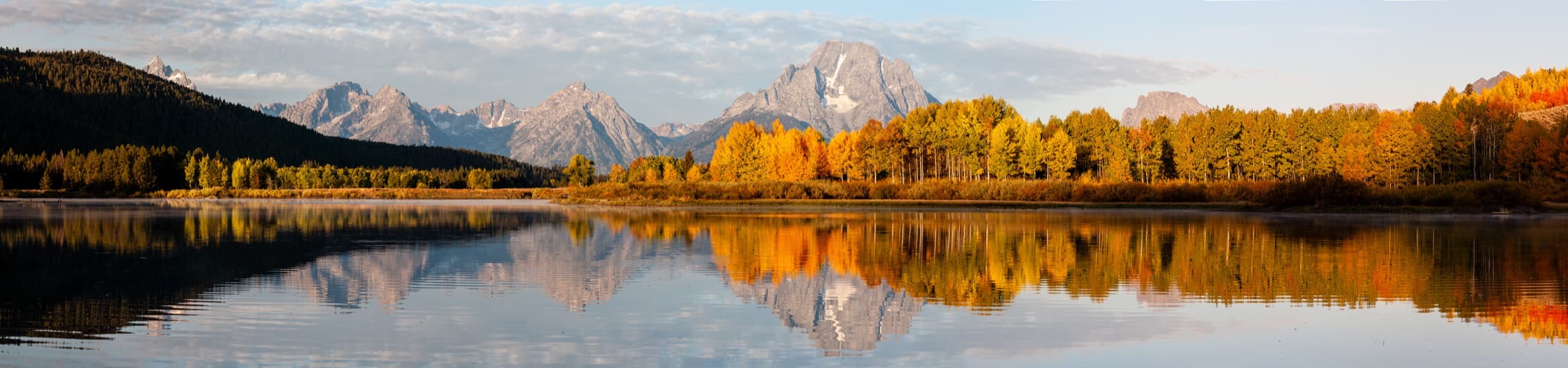 Mountain peaks reflected in a lake surrounded by autumn foliage
